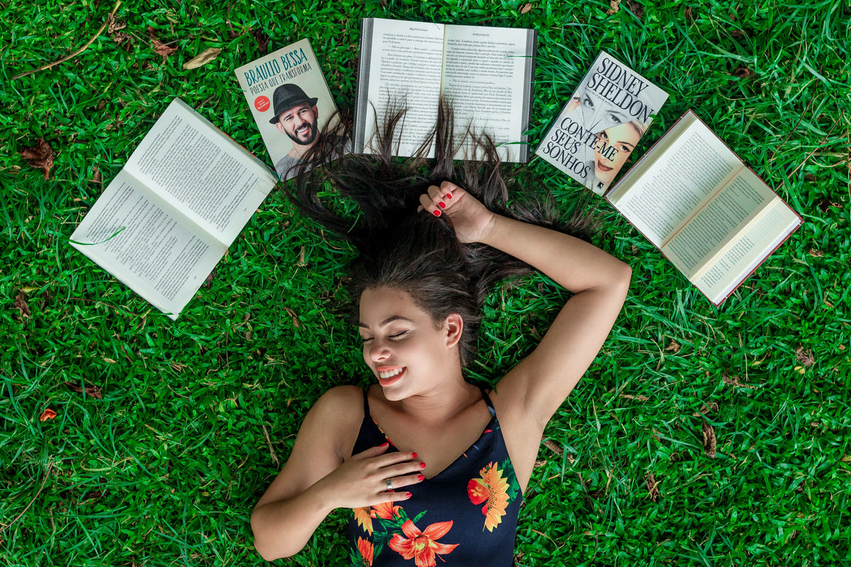 Lettrice sul prato tra libri aperti